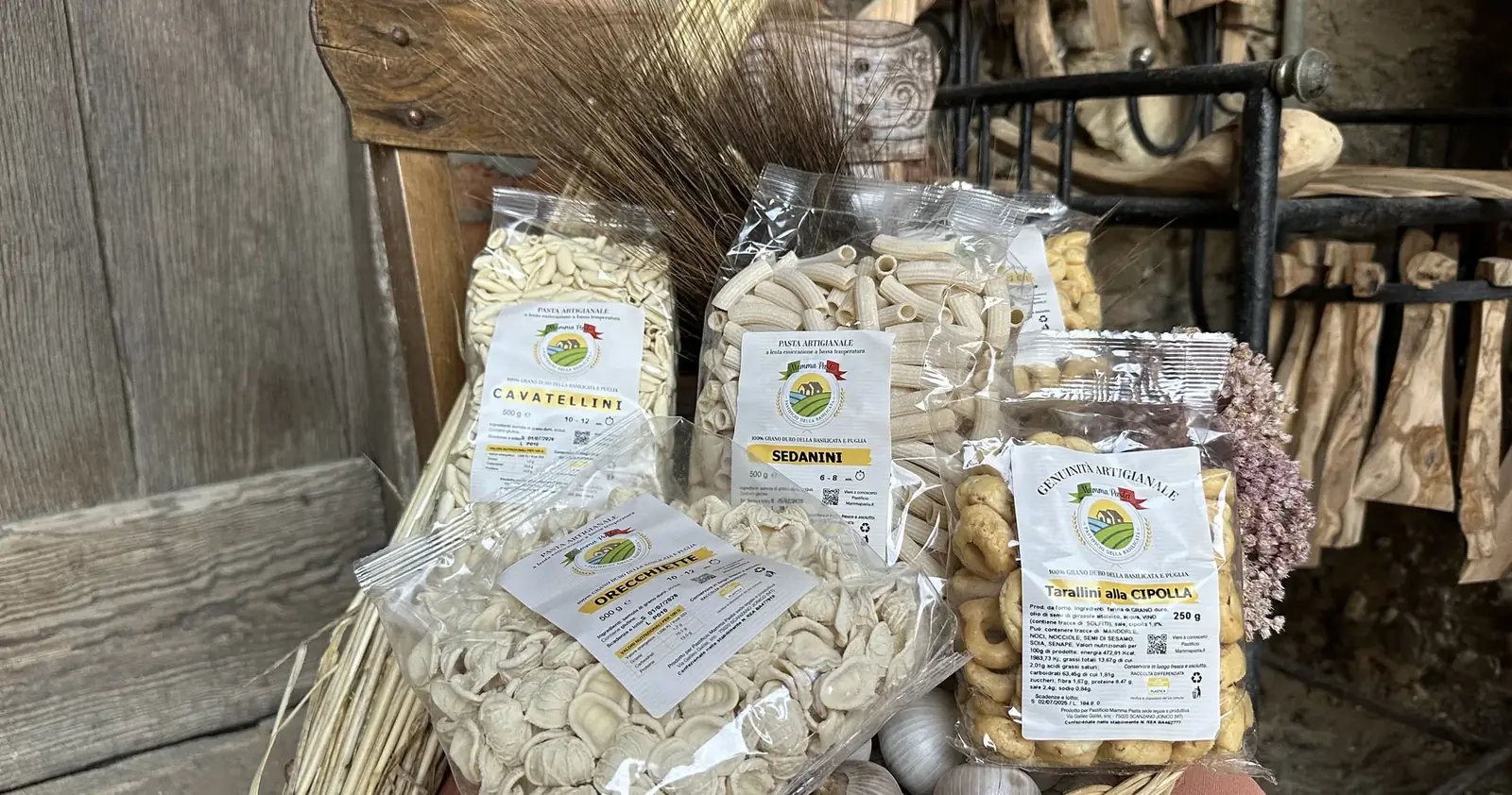 Un cesto di vimini con cavatellini, sedanini, orecchiette e tarallini alla cipolla, davanti alla vecchia porta del pastificio